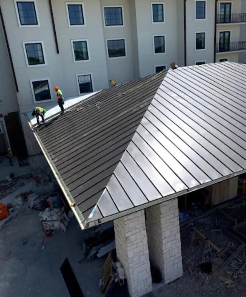 Crew installing standing seam metal roof panels on a commercial project in Conyers